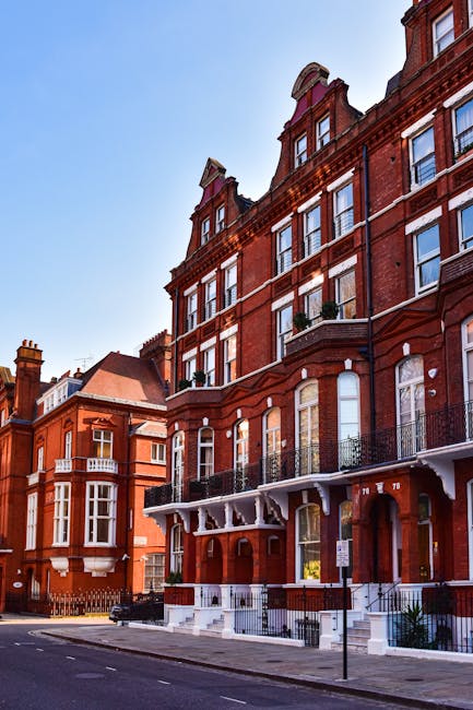 Image of a red brick residential building on Avenue Road NW3, featuring multiple floors with large, white-framed sash windows. The building has black wrought iron balconies on the lower levels, and so